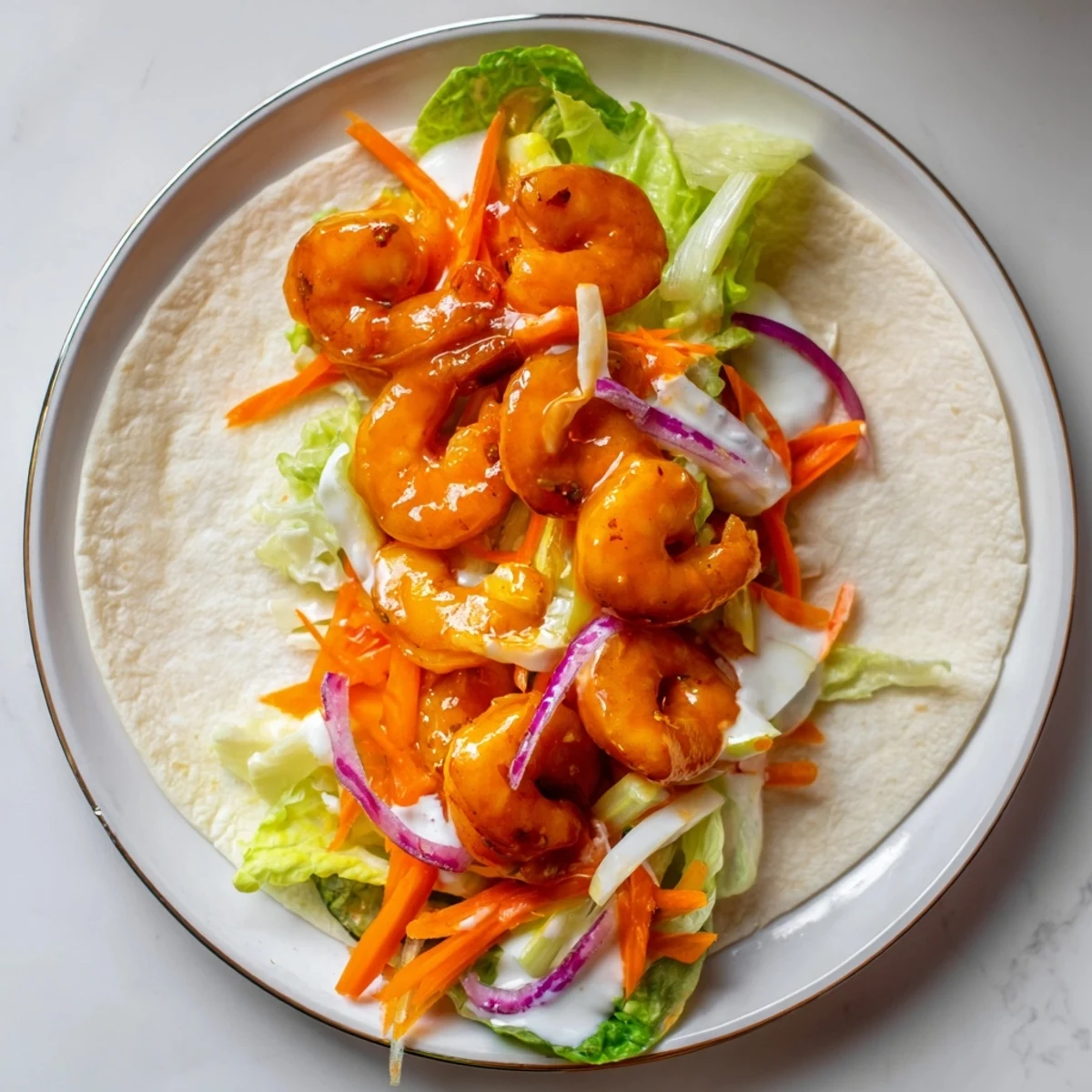 Bright red buffalo shrimp wraps bursting with fresh veggies and creamy dressing, perfect for lunch.