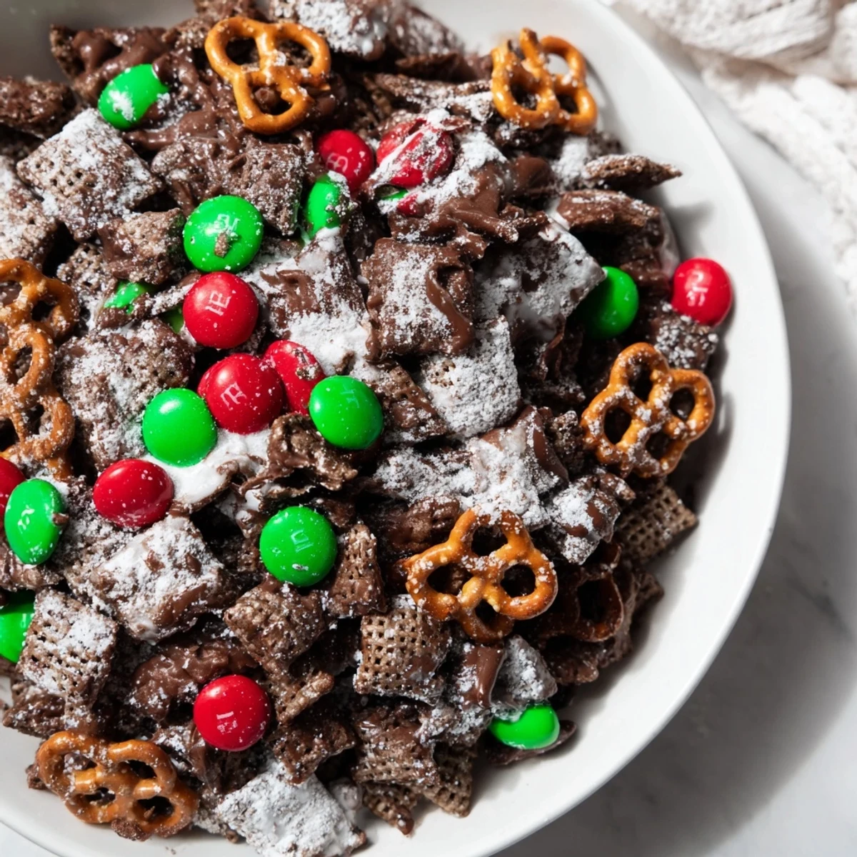 Festive Simplified Reindeer Chow mix coated in powdered sugar and chocolate, a delightful holiday snack.