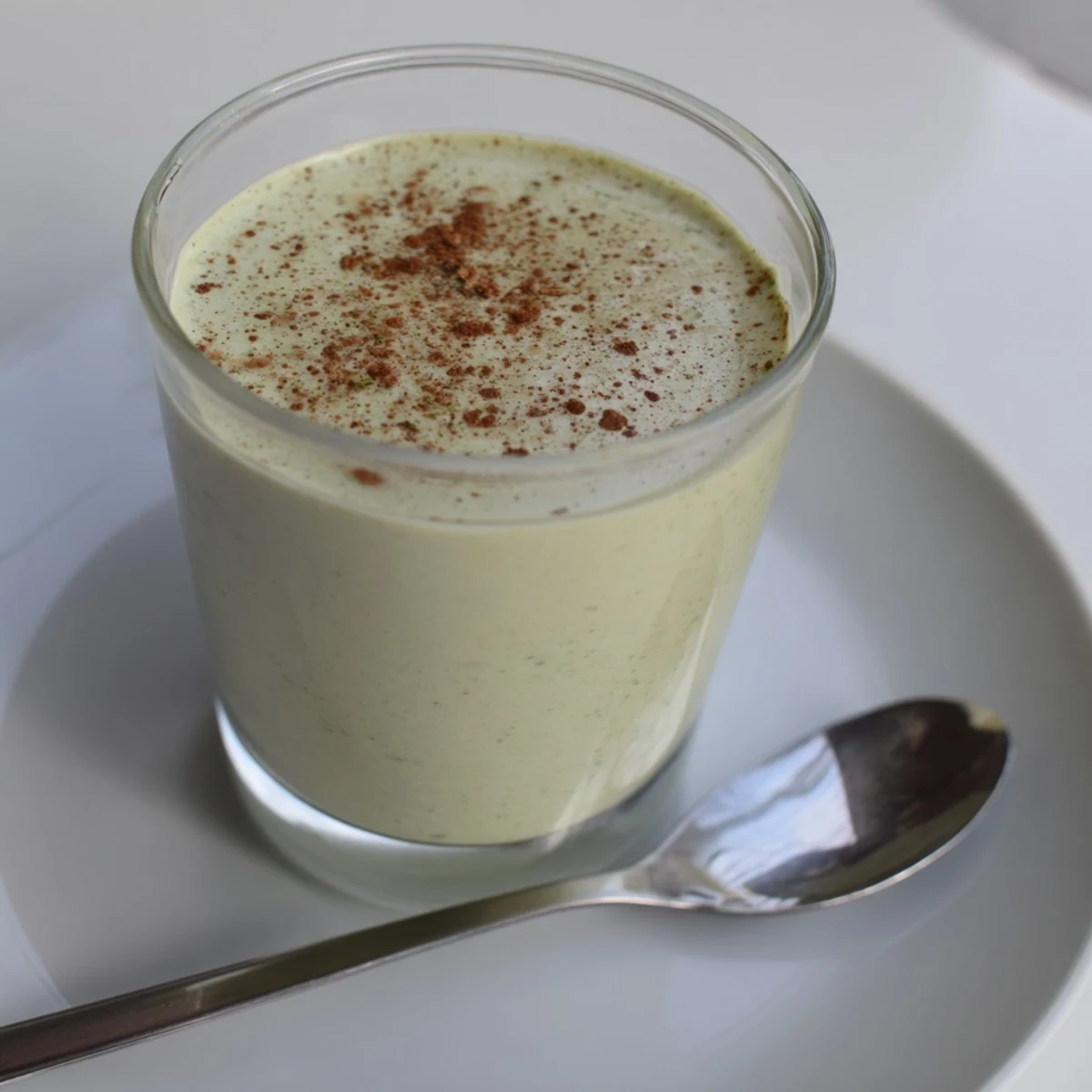 A vibrant green Matcha Eggnog Collagen Breakfast Smoothie, swirled in a tall glass, ready to enjoy.