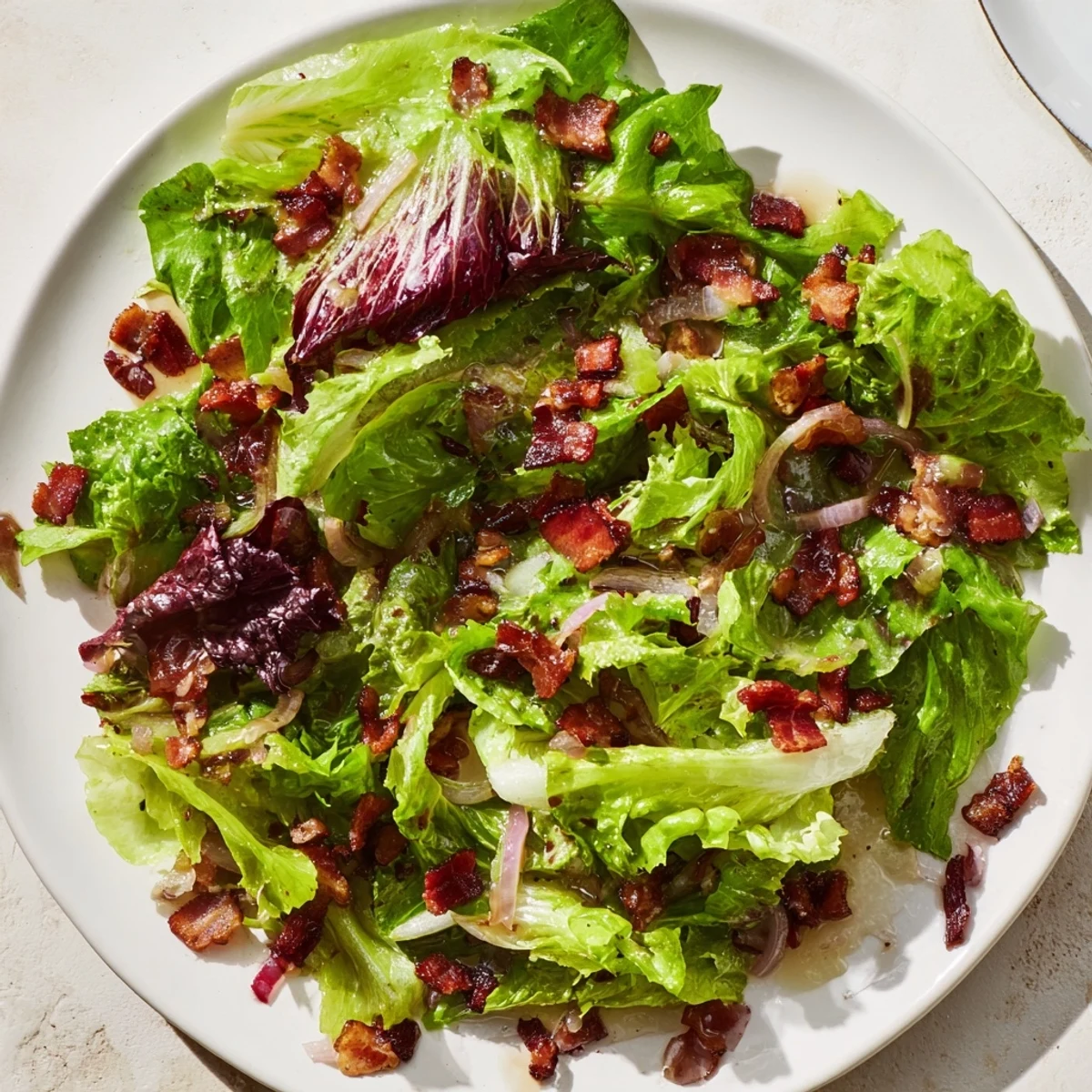 Freshly tossed Bitter Greens Salad, visually vibrant with its warm bacon dressing, ready to enjoy.