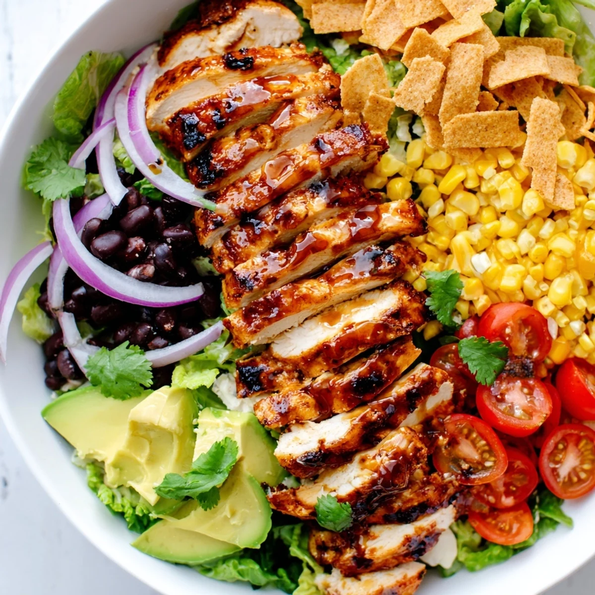 A colorful bowl of honey lime chicken taco salad with romaine, black beans, tomatoes, and cheese.