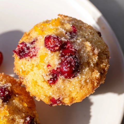 Warm, golden Quick Festive Cranberry Orange Muffins overflowing with juicy cranberries, perfect for serving.