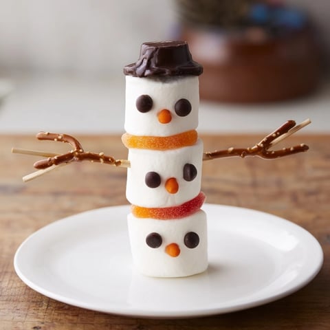 Marshmallow snowman sticks arranged, showing sweet, playful treats decorated with chocolate facial features.