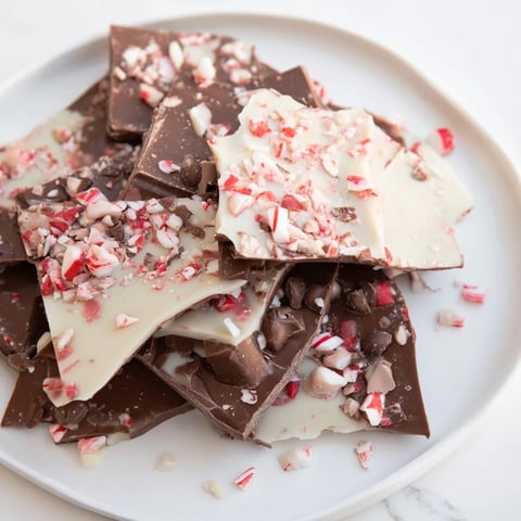 Peppermint Bark shards, a colorful dessert, scattered on a wooden board ready to be enjoyed.