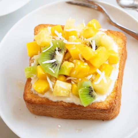 Creamy Yogurt-Custard Toast drizzled with honey and garnished with fresh kiwi and mango.  
