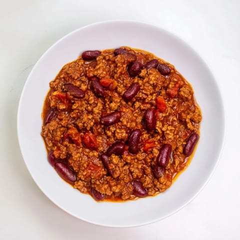 A steaming bowl of flavorful Secret 4-Ingredient Chili, garnished with fresh toppings, perfect for dinner.