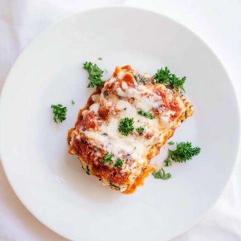 Tender pasta sheets are filled with a savory chicken, spinach, and three-cheese mixture, bubbling with marinara in a cozy serving dish.