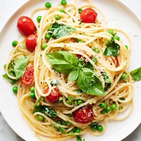 Colorful spring vegetables and al dente spaghetti are tangled in a savory lemon-infused sauce for a quick meal.
