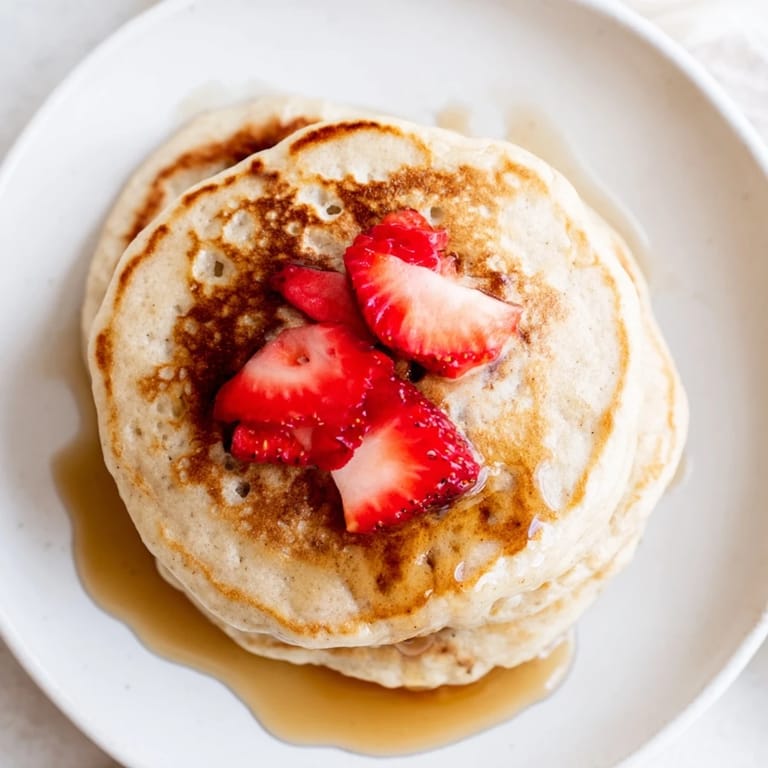Stack of light and airy Protein Banana Pancakes, served with fresh berries, ready to eat.