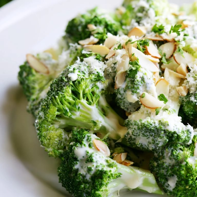 A chilled side of Garlic Parmesan Broccoli Salad garnished with grated Parmesan and crunchy sunflower seeds.