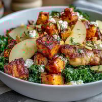 Freshly roasted chicken and caramelized sweet potatoes top a vibrant Fall Sweet Potato Harvest Bowl with kale and crisp apple slices.